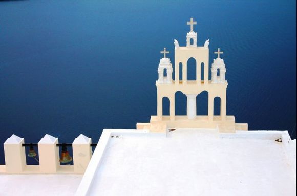 The graceful architecture of a church against the backdrop of the Aegean sea.
