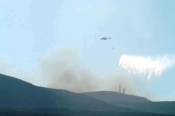 The fire rescue helicopter dumps a load of water over bushfires in August 2010 behind the ranges at Diakofti.