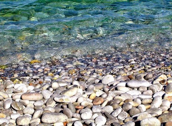 Large pebbles, a little hard on the feet, but lead to the most crystal clear water, at Plaka's shores.