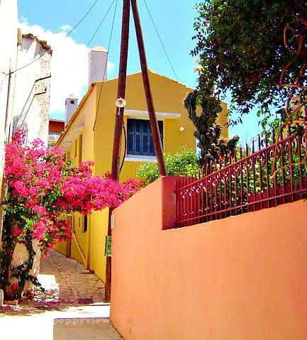 A stone path, canopied in pink bougainvillea, invites me to pass through its narrow lane way, lined with traditional houses, painted in rich, warm hues.